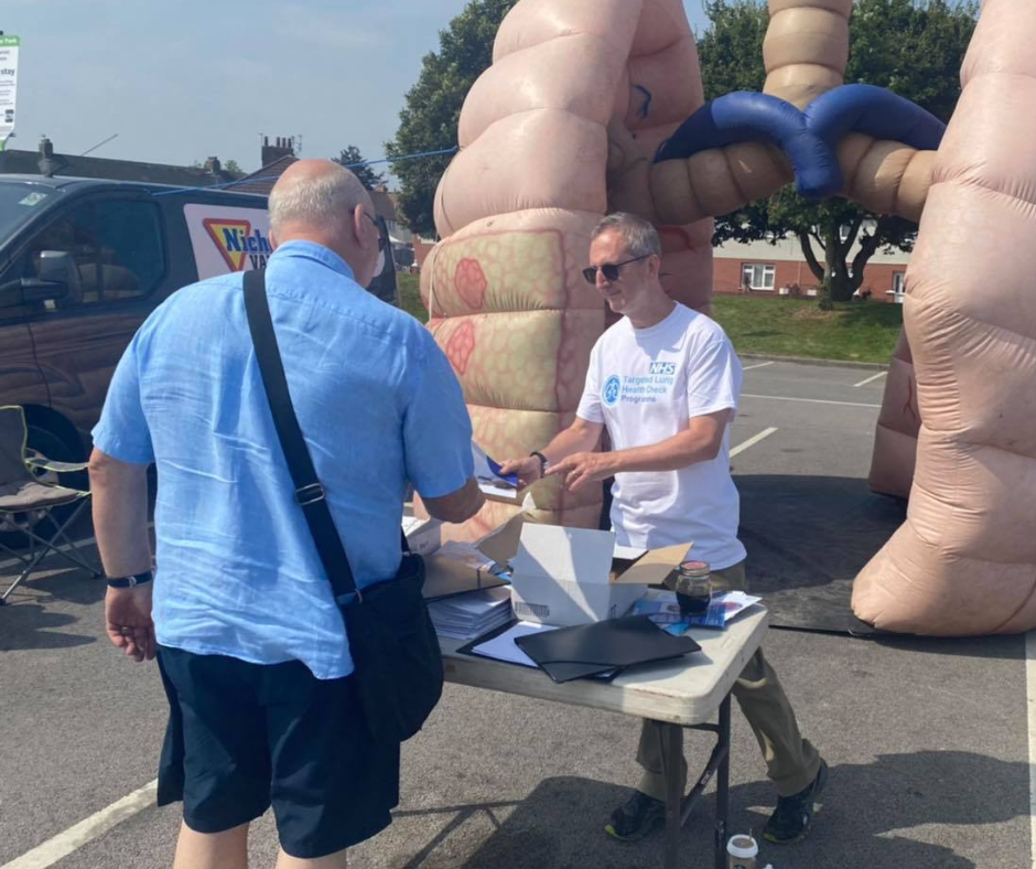 A photo of two men standing in front of an information stall and a large inflatable pair of lungs