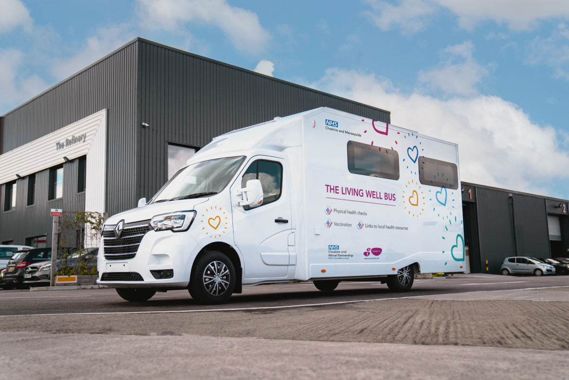 A white van with drawings of hearts and the words "NHS Cheshire and Merseyside. The Living Well Bus. Physical Health Checks. Vaccinations. Links to local health resources." printed on it.